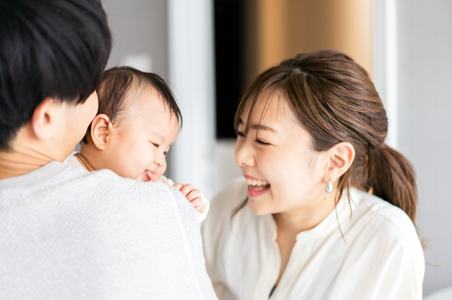 女性の笑顔と幼児を抱く男性